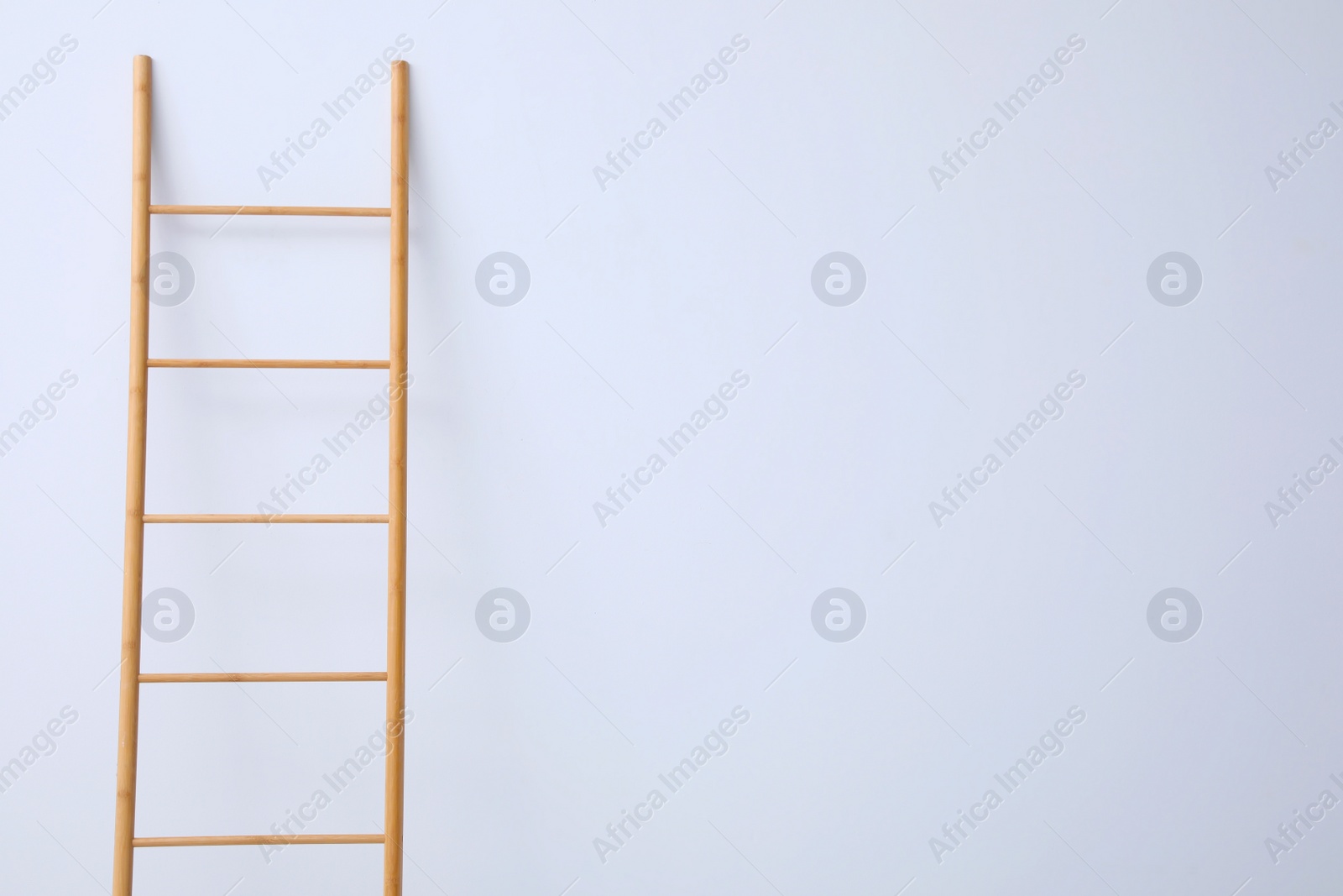 Photo of Modern wooden ladder on white background. Space for text