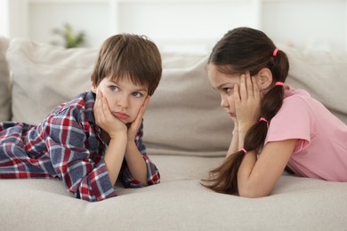 Photo of Upset brother and sister on sofa at home