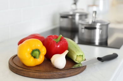 Photo of Fresh vegetables and knife on white counter in kitchen
