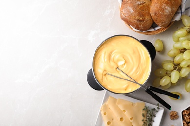 Photo of Flat lay composition with pot of delicious cheese fondue and space for text on gray table