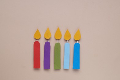 Different paper candles on beige background, flat lay