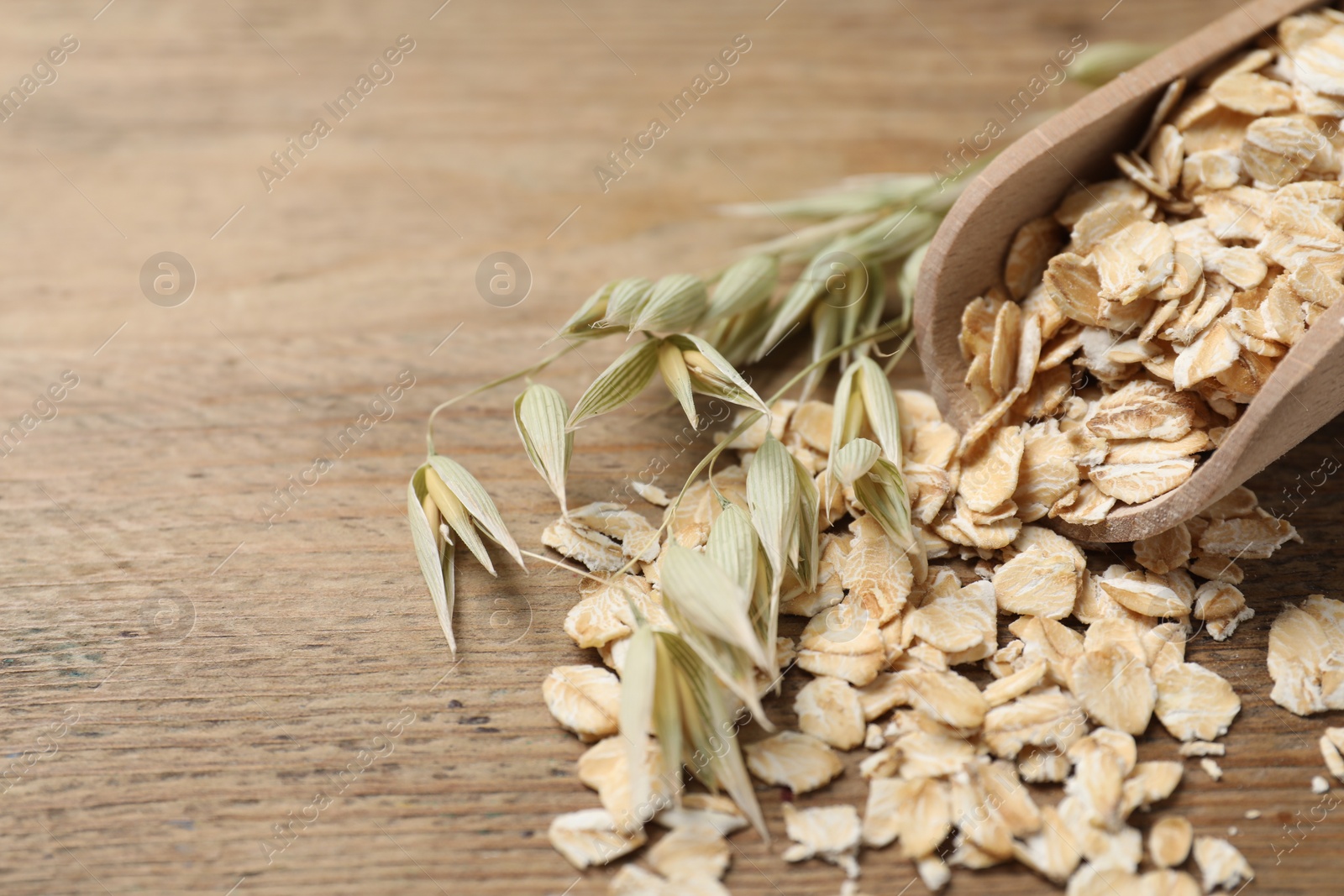 Photo of Scoop with oatmeal and florets on wooden table, closeup. Space for text