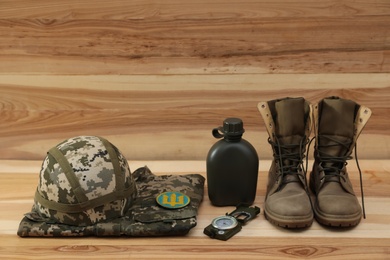 Photo of MYKOLAIV, UKRAINE - SEPTEMBER 26, 2020: Tactical gear and Ukrainian military uniform on wooden background. Space for text