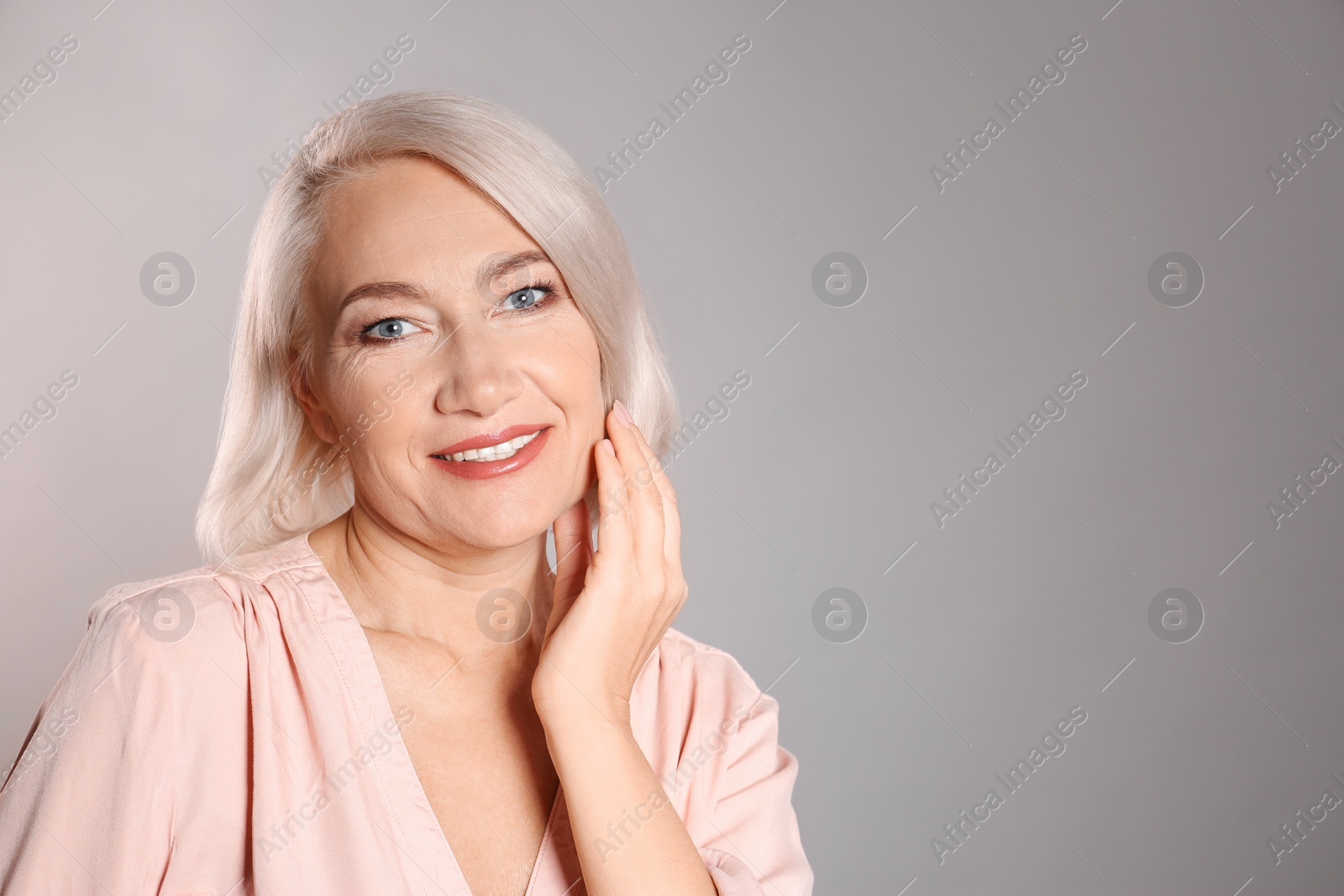 Photo of Portrait of charming mature woman with healthy beautiful face skin and natural makeup on grey background, space for text