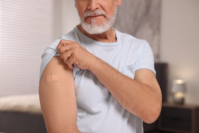 Man with adhesive bandage on his arm after vaccination indoors, closeup