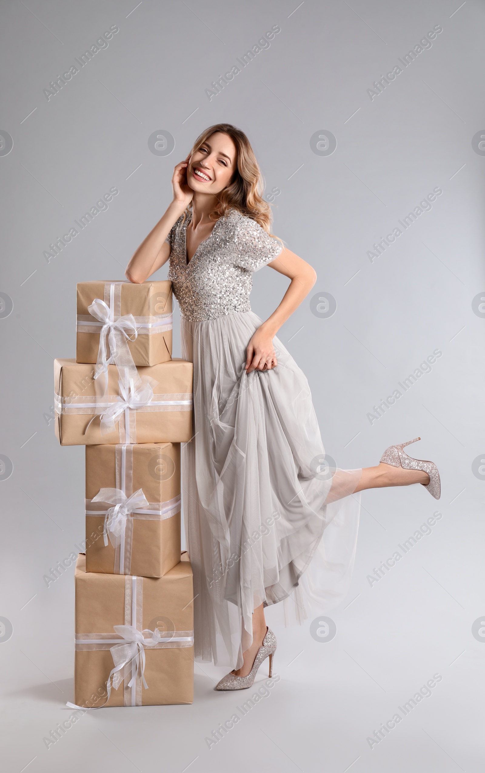 Photo of Beautiful young woman with Christmas presents on light grey background