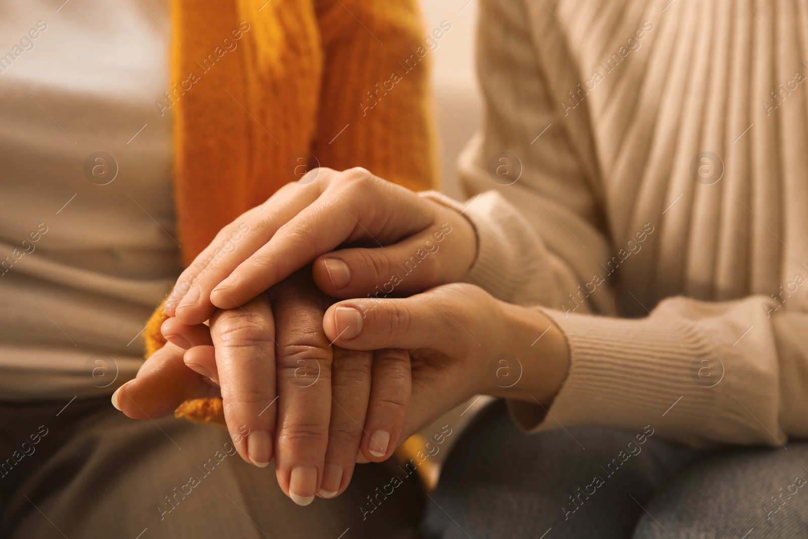 Photo of Young and elderly women holding hands together, closeup