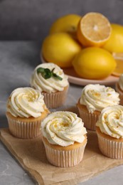 Photo of Delicious cupcakes with white cream and lemon zest on table, closeup