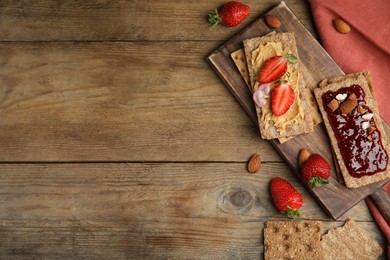 Photo of Fresh rye crispbreads with different toppings on wooden table, flat lay. Space for text