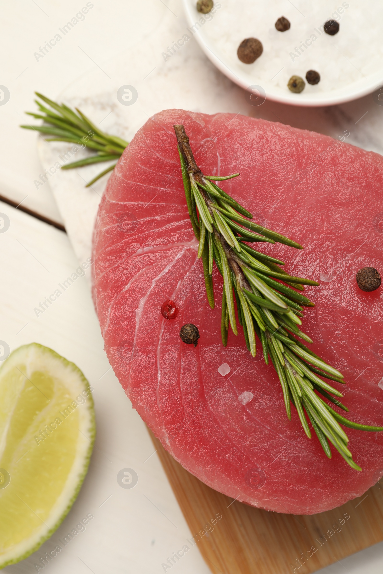 Photo of Raw tuna fillet with rosemary and spices on white table, top view