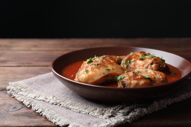 Photo of Tasty cooked rabbit meat with sauce and parsley on wooden table