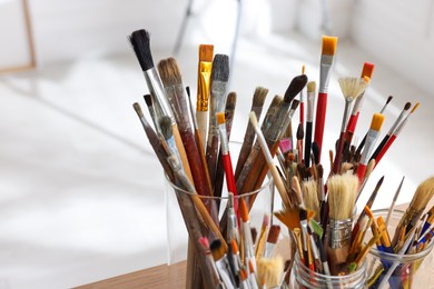 Photo of Holders with many different paintbrushes indoors, closeup