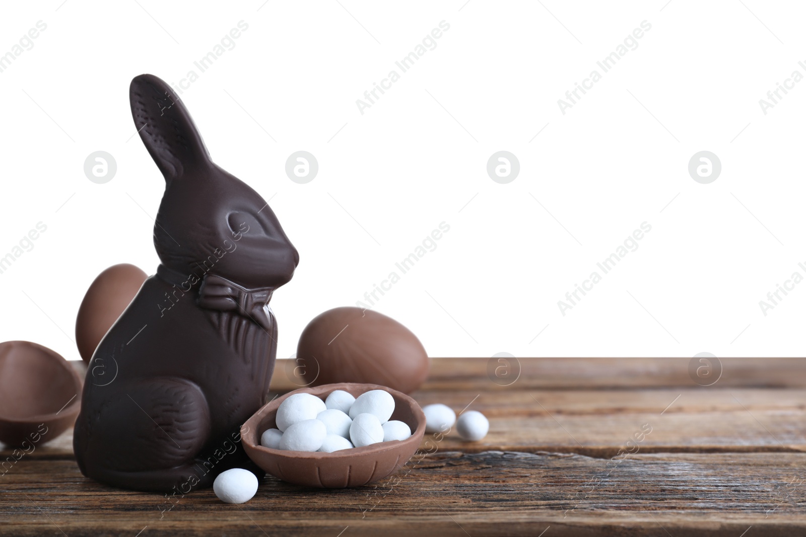 Photo of Dark chocolate Easter bunny and eggs on wooden table against white background. Space for text