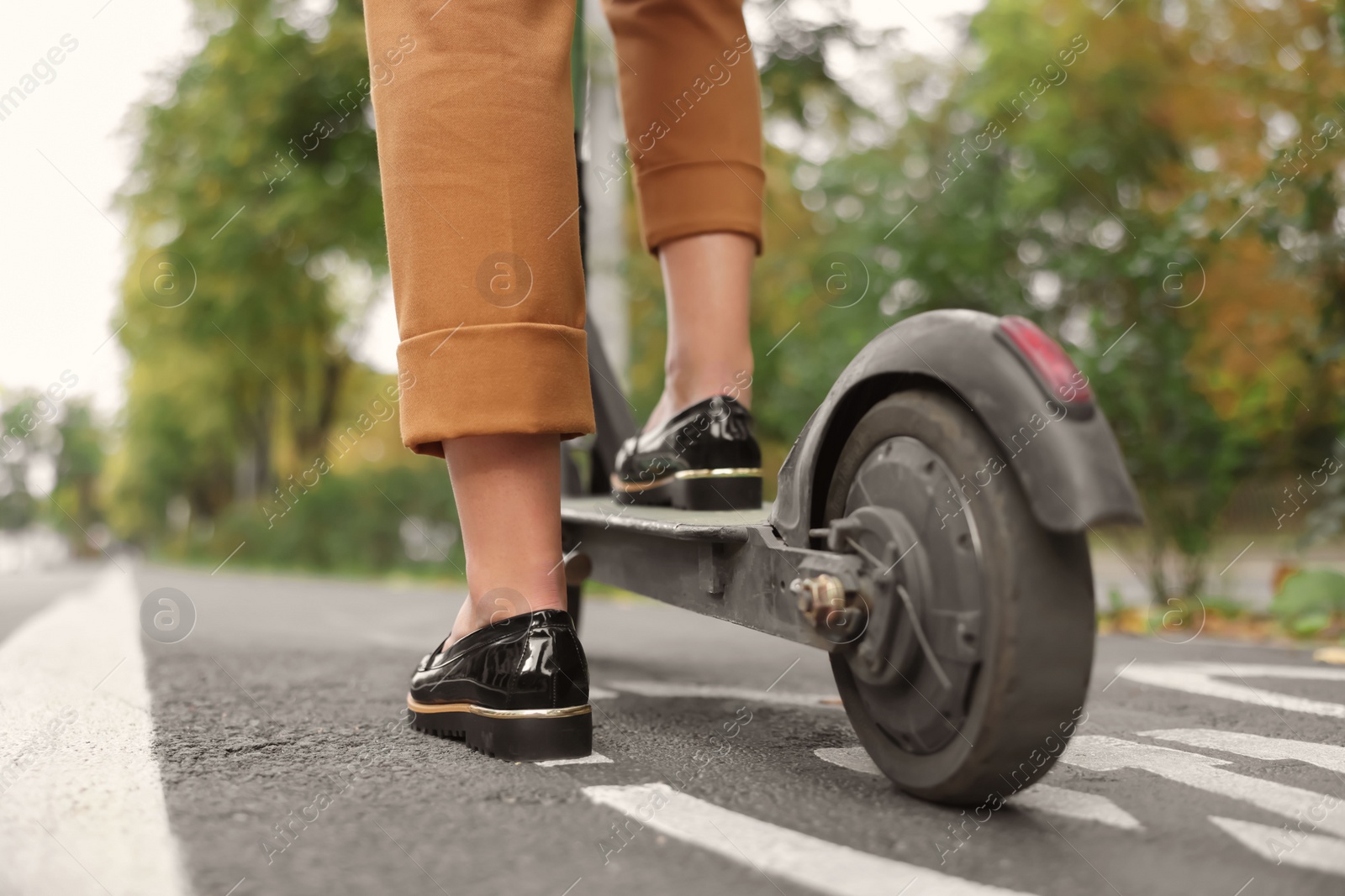 Photo of Businesswoman with modern electric kick scooter on city street, closeup