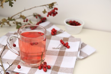 Photo of Cup with hawthorn tea and berries on table. Space for text