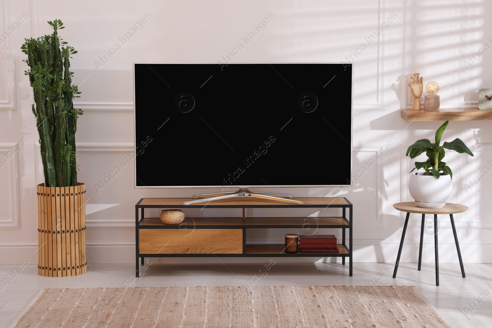 Photo of Modern TV on stand near white wall indoors. Interior design