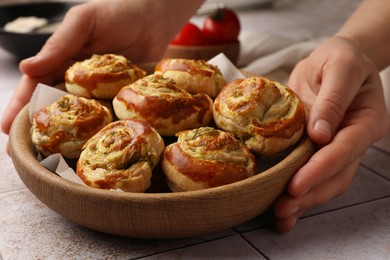 Photo of Woman putting wooden bowl with fresh delicious puff pastry on table, closeup