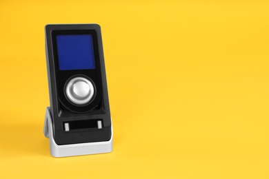 Modern remote for audio speakers on yellow background, space for text