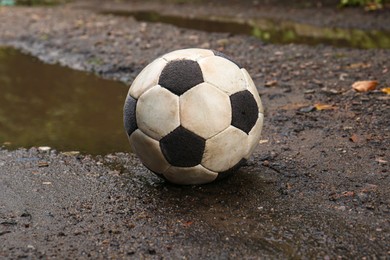 Photo of Dirty soccer ball near puddle on ground