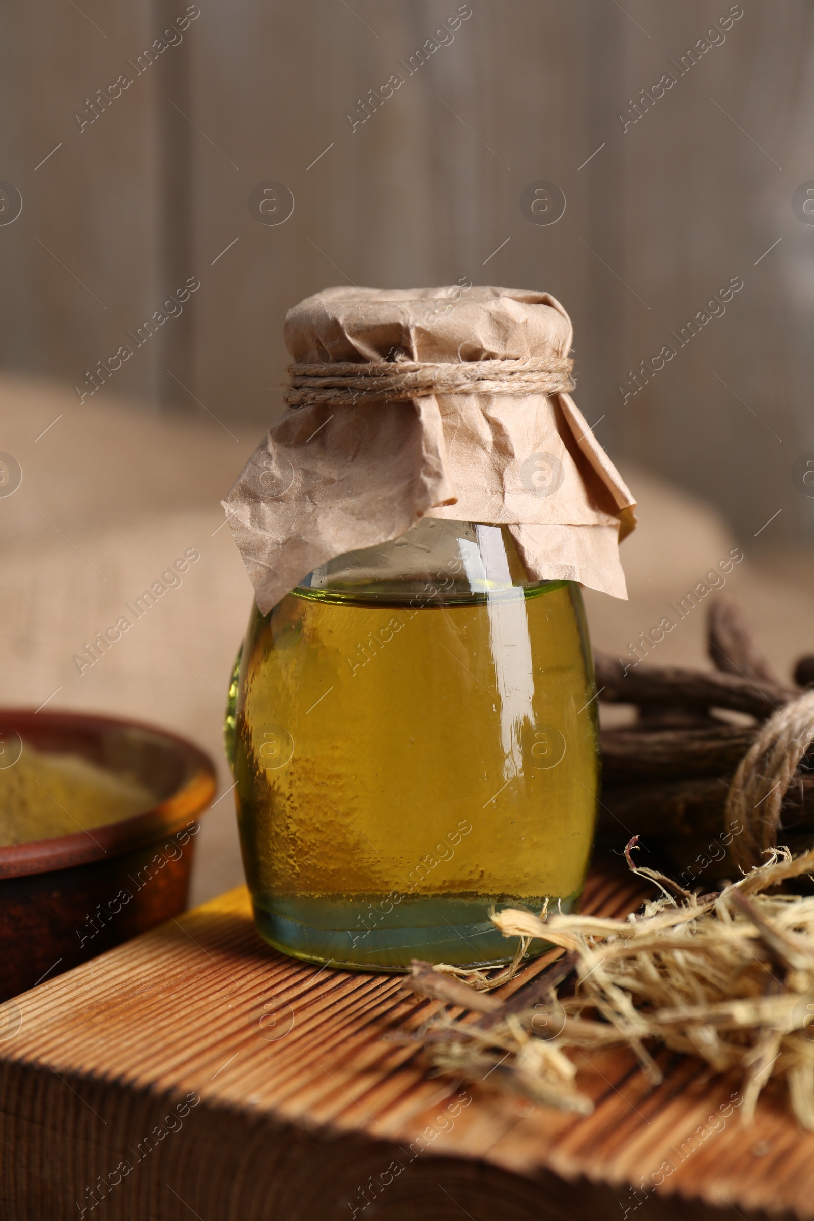 Photo of Dried sticks of licorice root and essential oil on wooden board, closeup