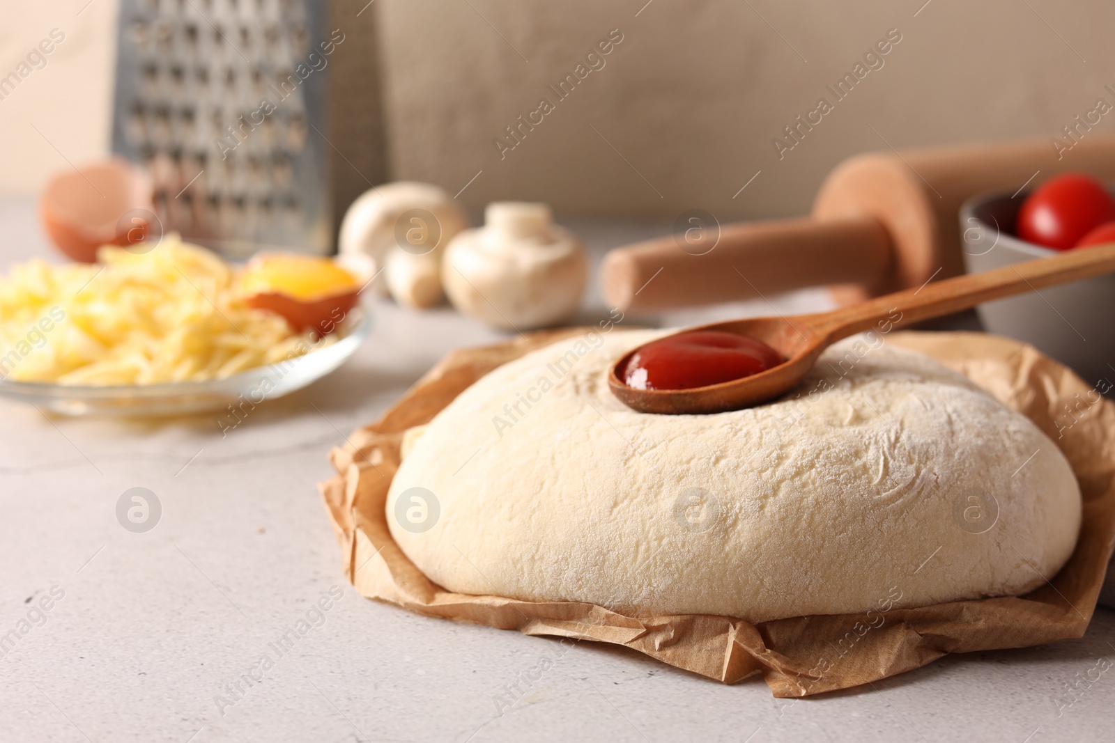 Photo of Pizza dough and products on gray textured table, closeup