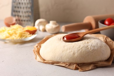 Photo of Pizza dough and products on gray textured table, closeup