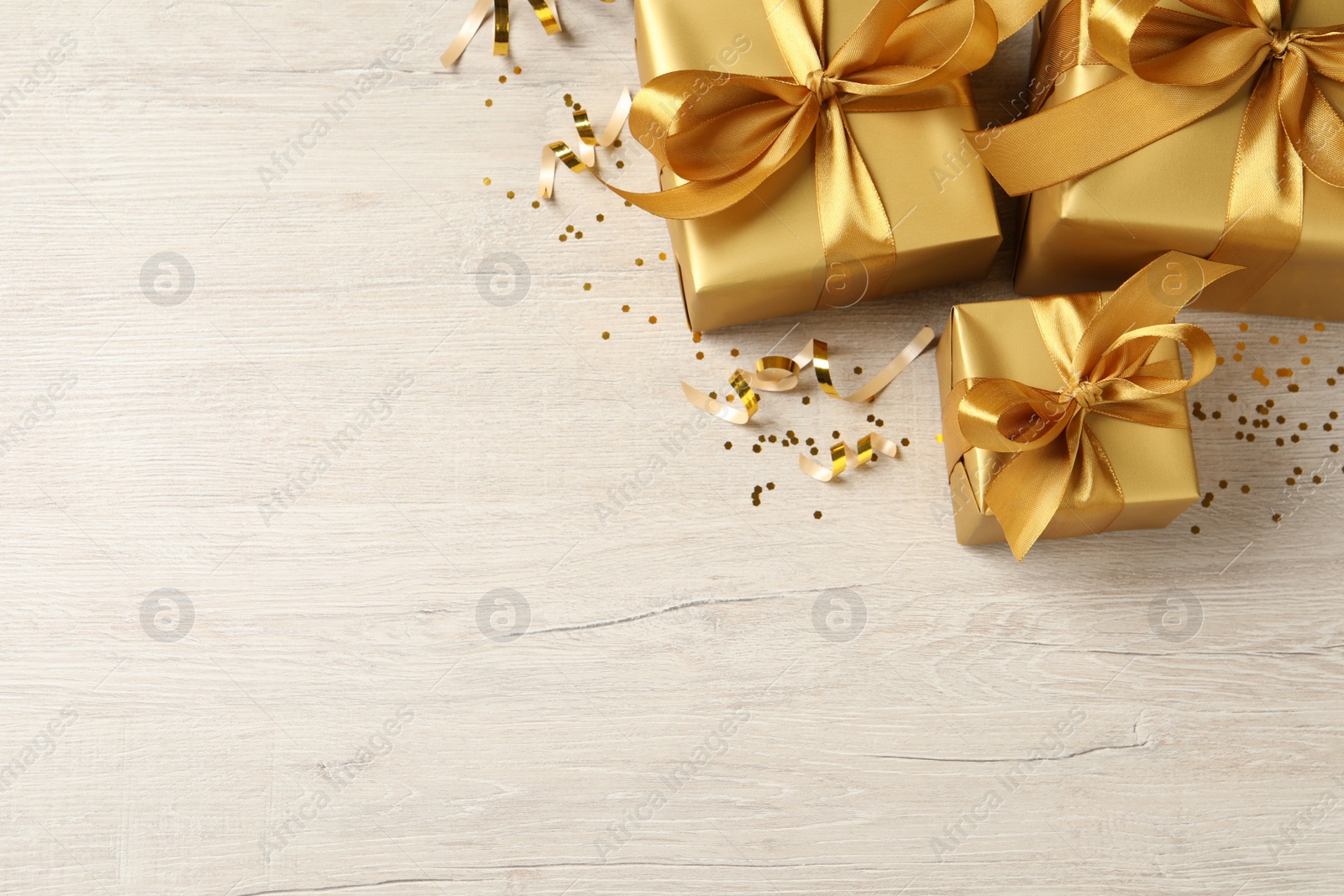 Photo of Beautifully wrapped gift boxes and confetti on white wooden table, flat lay. Space for text