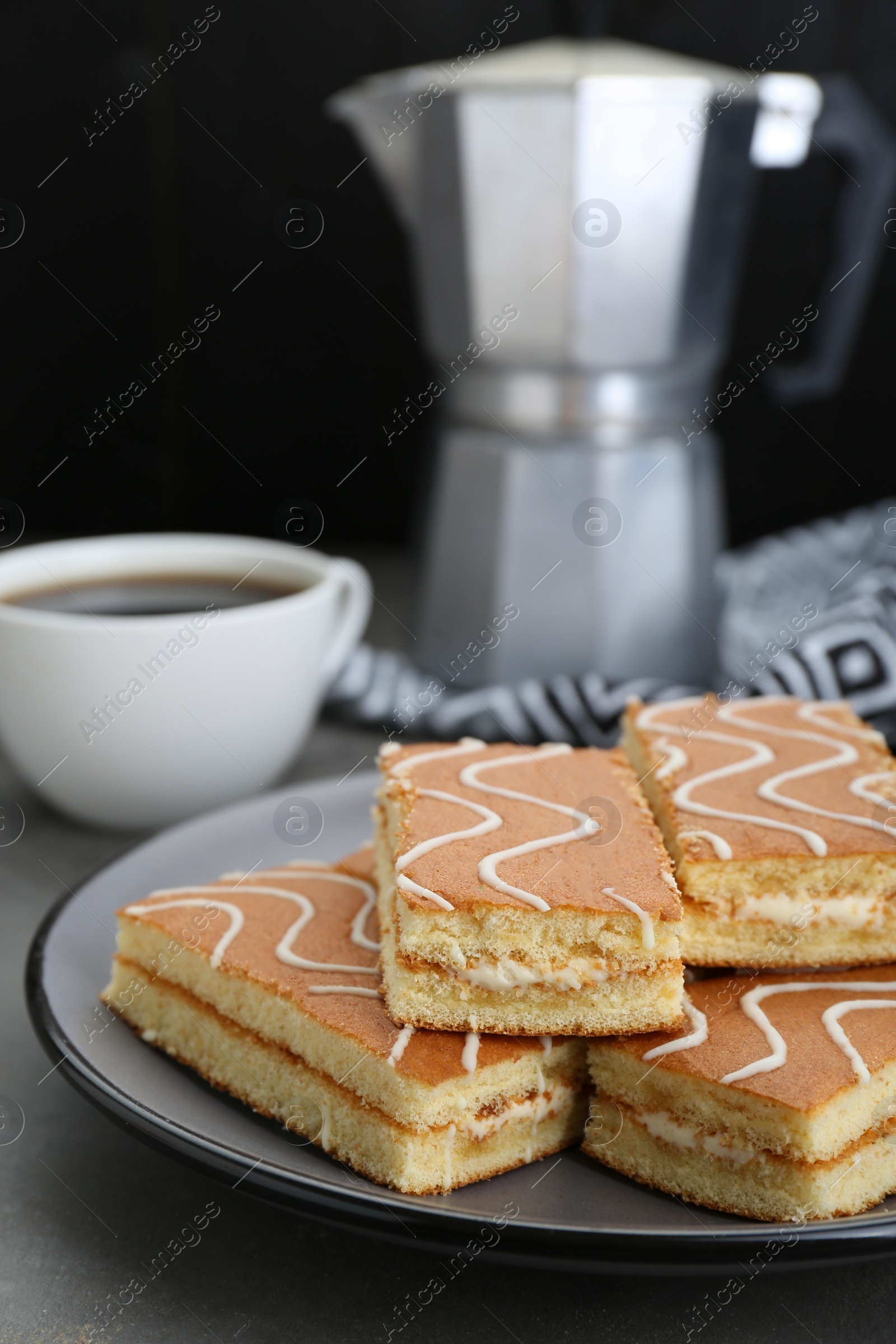 Photo of Tasty sponge cakes and hot drink on grey table, closeup