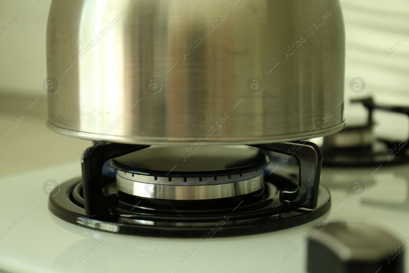 Photo of Kettle on gas burner of stove in kitchen, closeup