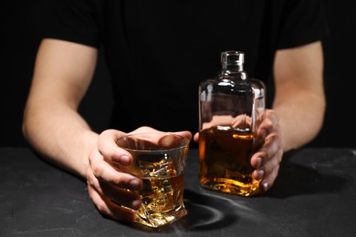 Photo of Alcohol addiction. Man with whiskey at dark textured table, selective focus