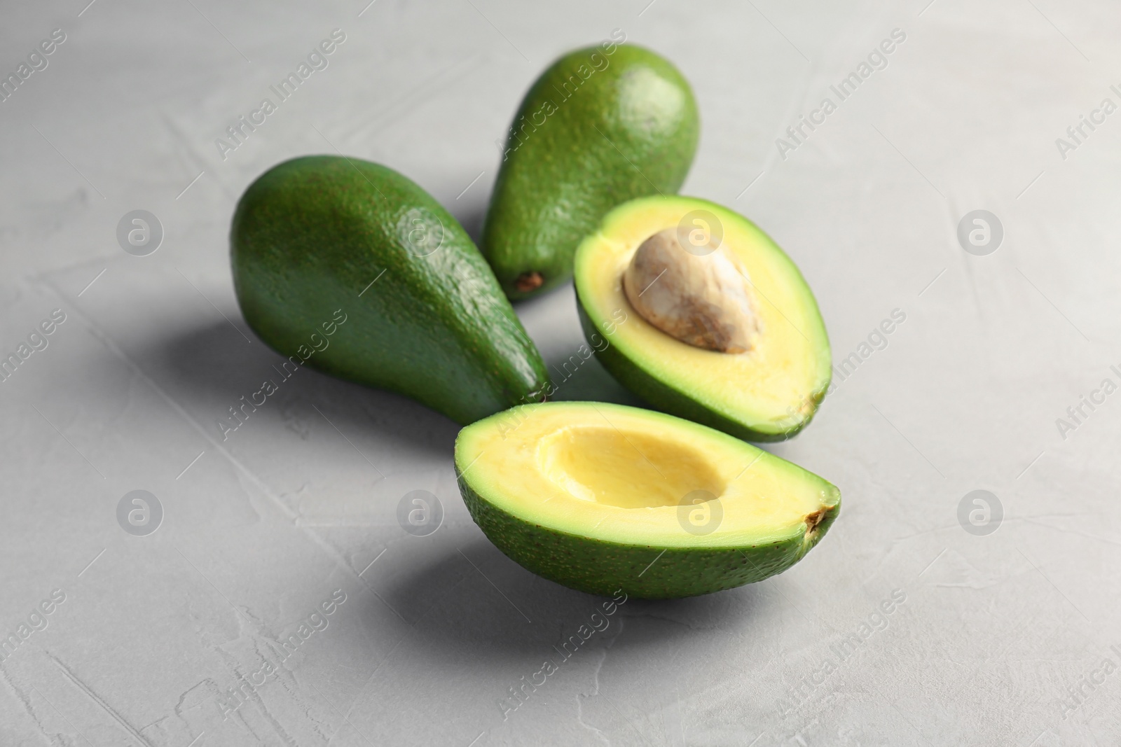 Photo of Tasty ripe green avocados on grey background