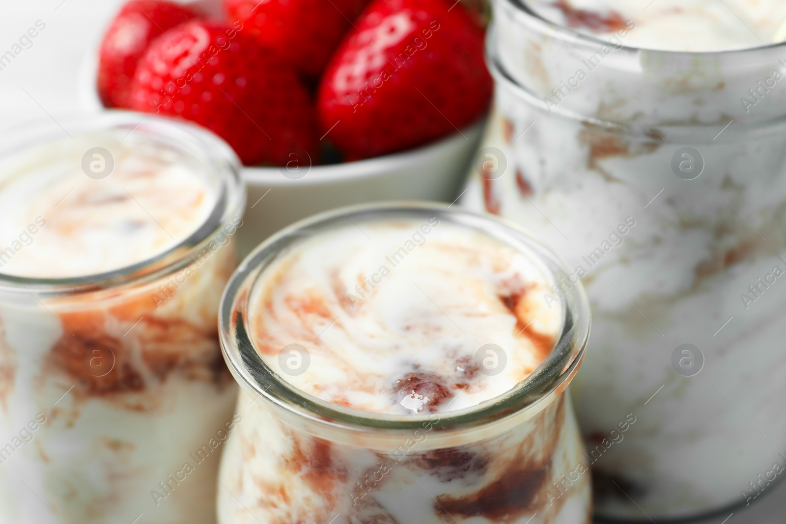 Photo of Tasty yoghurt with jam and strawberries on table, closeup