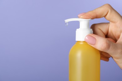 Photo of Woman using cleansing gel on violet background, closeup. Space for text