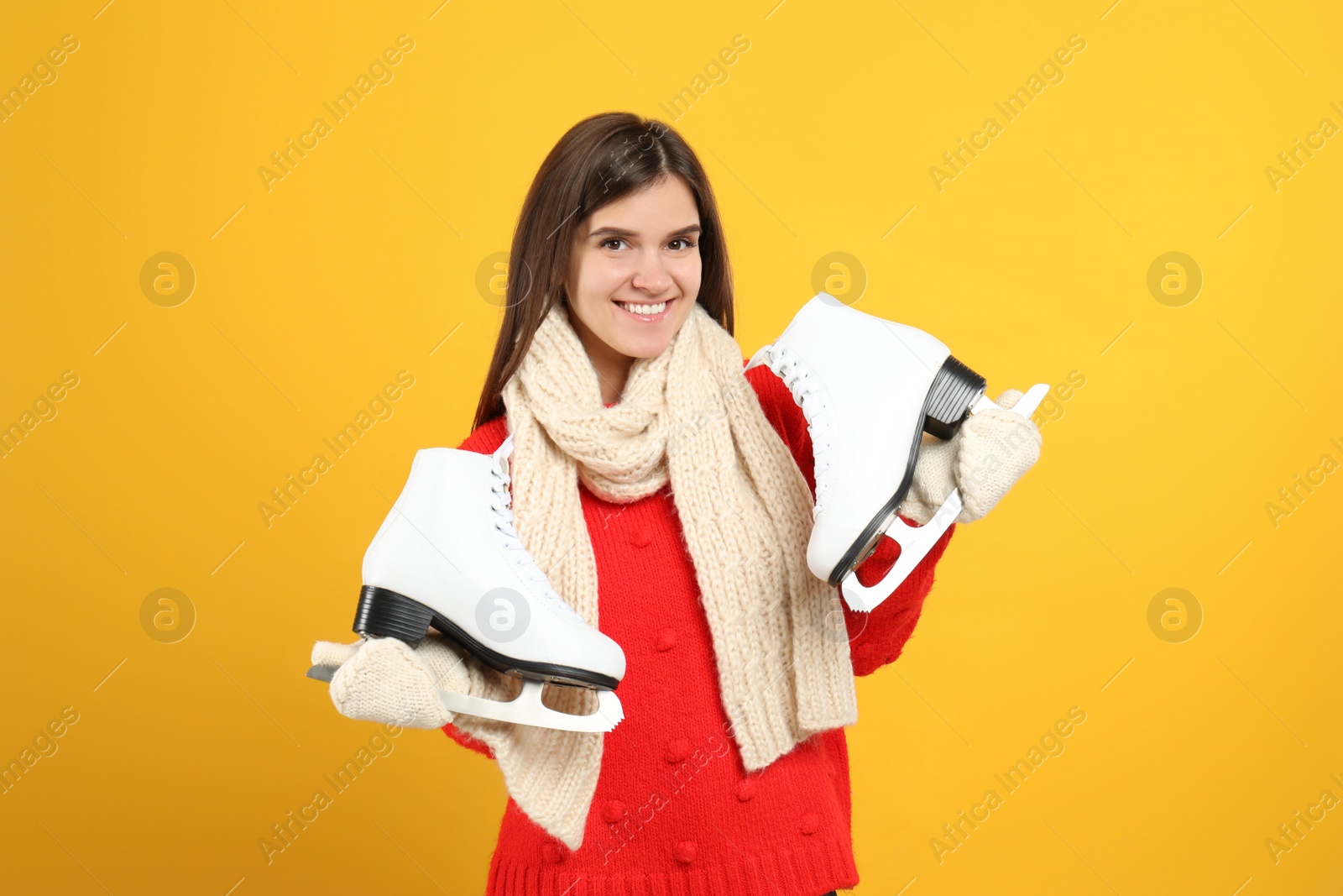 Photo of Happy woman with ice skates on yellow background