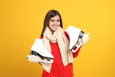 Photo of Happy woman with ice skates on yellow background