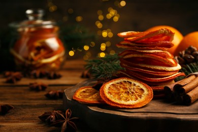 Photo of Dry orange slices, anise stars and cinnamon sticks on wooden table, space for text. Bokeh effect