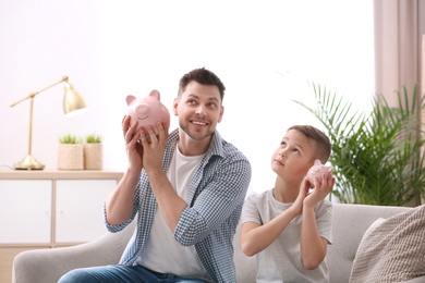 Father and son with piggy banks at home