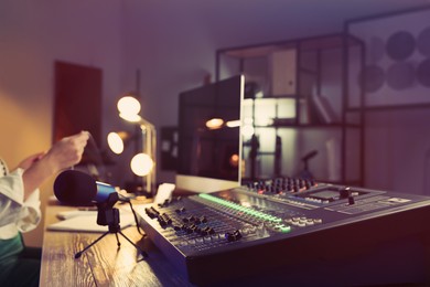 Woman working as radio host in modern studio, focus on professional mixing console. Space for text