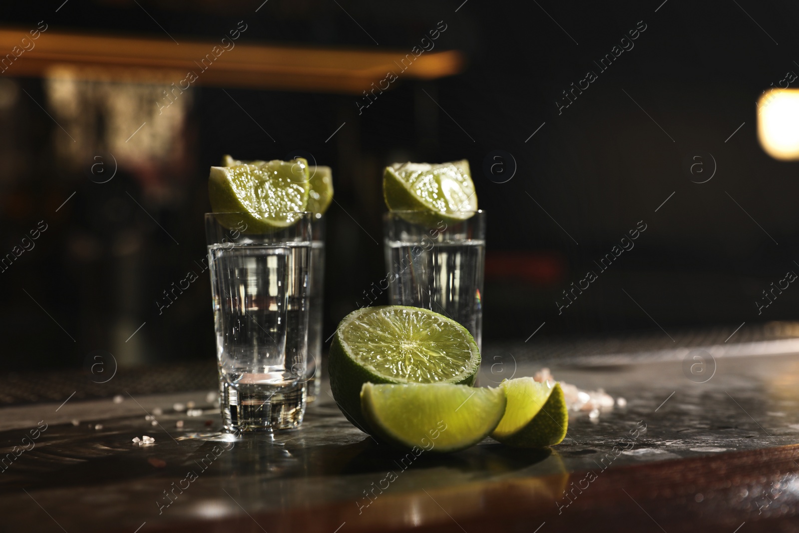 Photo of Mexican Tequila shots, lime slices and salt on bar counter