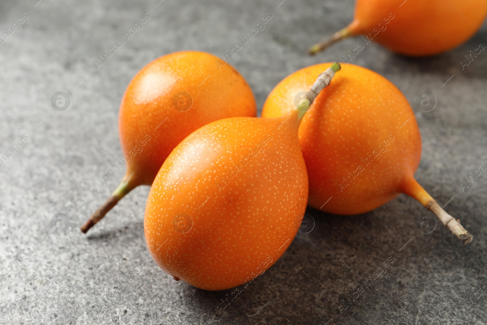 Photo of Whole delicious ripe granadillas on grey table