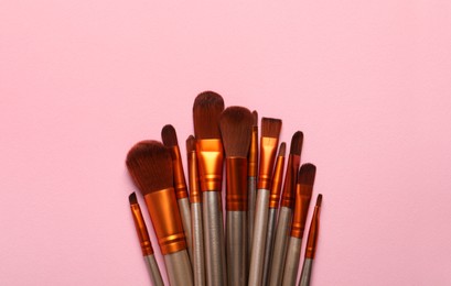 Set of makeup brushes on pink background, flat lay. Space for text