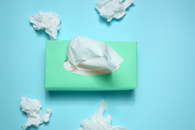 Photo of Used paper tissues and box on light blue background, flat lay