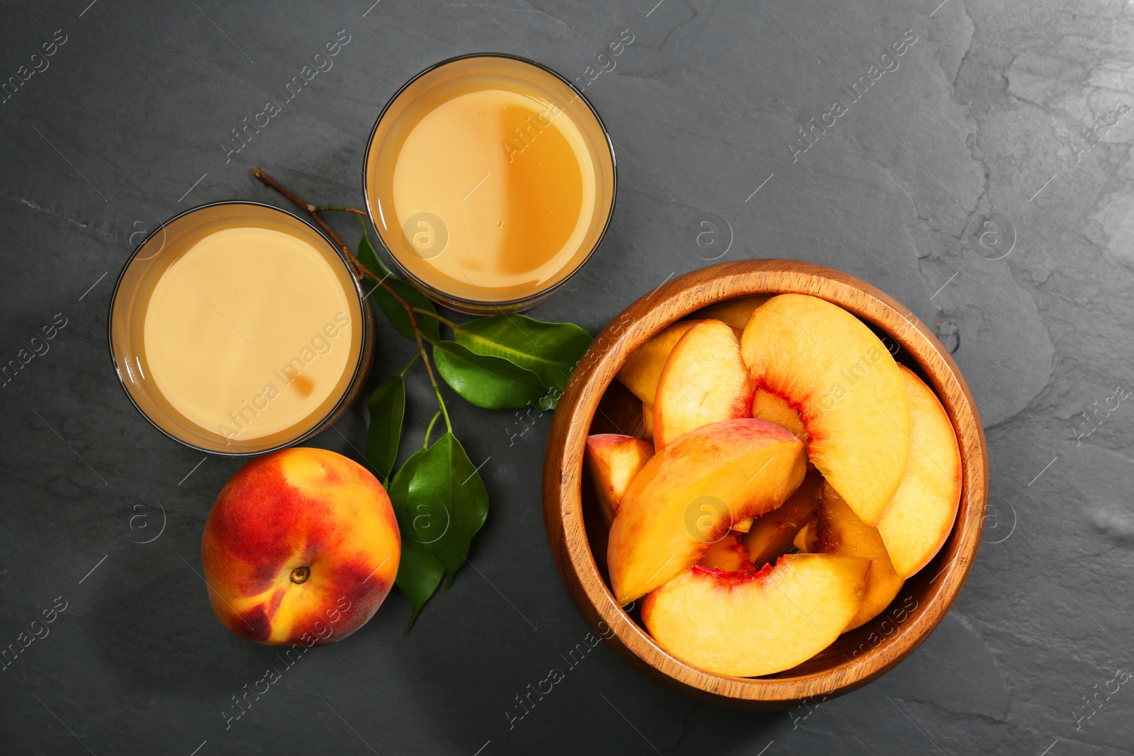 Photo of Glasses of delicious peach juice, fresh fruits and leaves on black table, flat lay