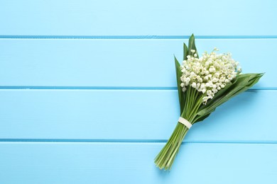 Beautiful lily of the valley bouquet on light blue wooden table, top view. Space for text