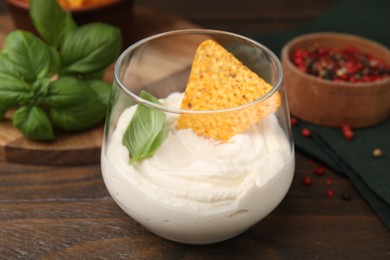 Photo of Delicious tofu sauce served with nachos chip on wooden table, closeup