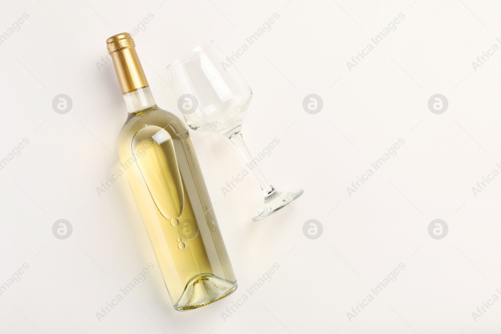 Photo of Bottle of expensive white wine and wineglass on light background, top view. Space for text