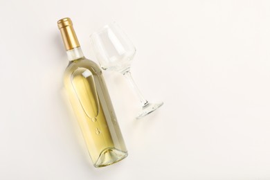 Photo of Bottle of expensive white wine and wineglass on light background, top view. Space for text