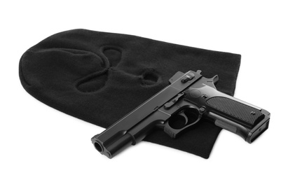 Photo of Black knitted balaclava and pistol on white background