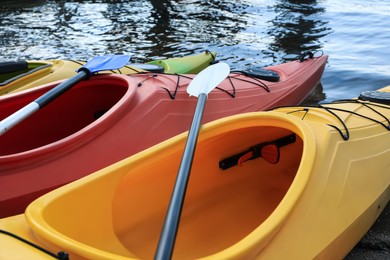Modern kayaks with paddles on river, closeup. Summer camp activity