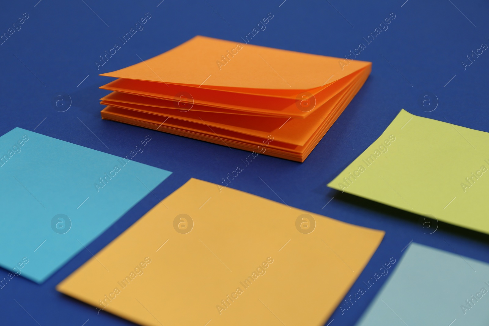 Photo of Colorful sticky notes on blue background, closeup